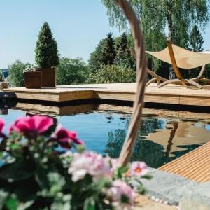 Auf diesem Bild ist ein von uns abgedichteter Koi Teich zusehen, rundherum ist eine Holzterrasse.